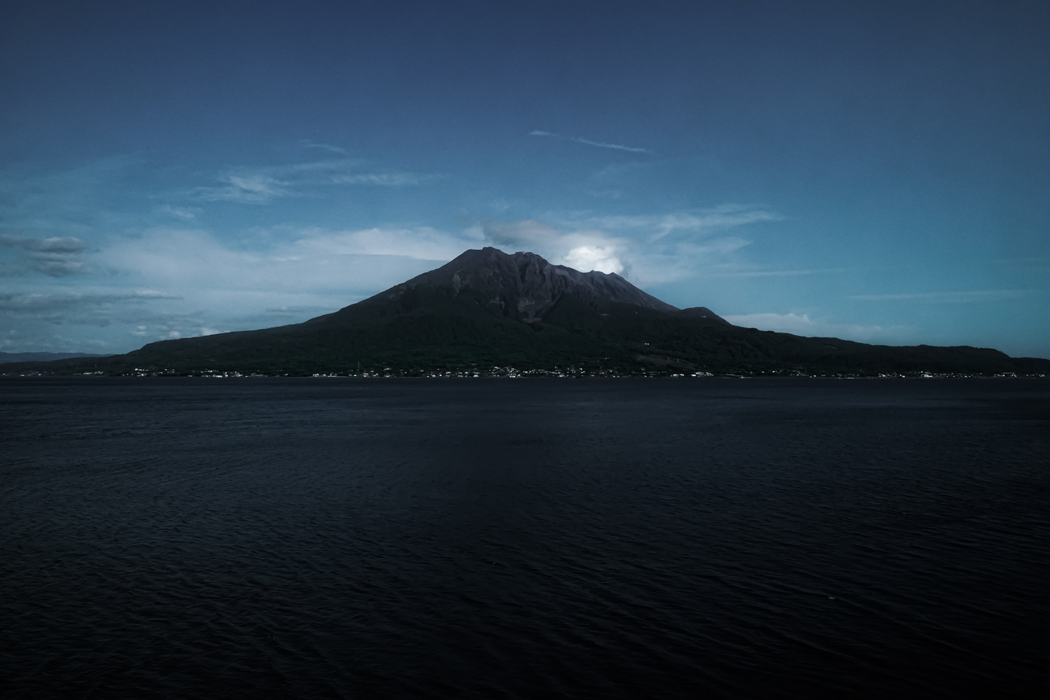 A panoramic view of Kagoshima, Japan, with the active volcano Sakurajima rising majestically in the distance.